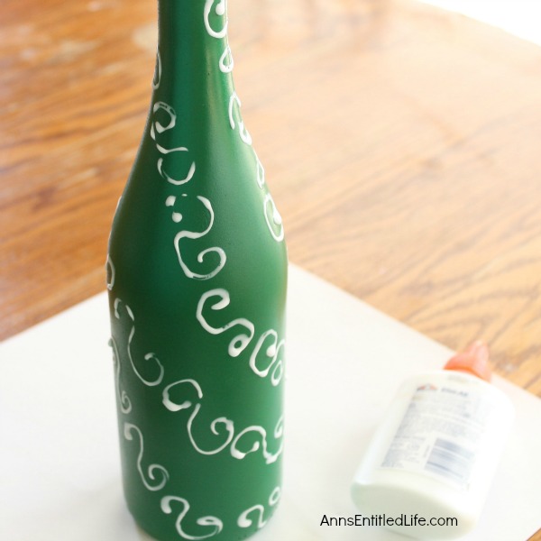 Easy DIY Wine Bottle Christmas Tree. An empty wine bottle, some glitter, paint and glue combined with a little imagination easily transforms into a pretty holiday decoration! Upcycle your empty wine bottles to make a lovely Christmas Tree decoration. Make one or make a grouping to form a centerpiece, mantel decoration, or unique side table decor.