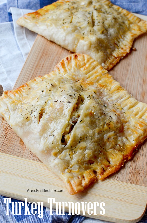 A large turkey turnover sits at the forefront on a cuttingboard. There is a second turkey turnover above it