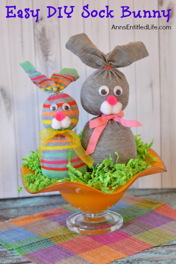 two sock bunnies in an orange bowl on top of green Easter grass