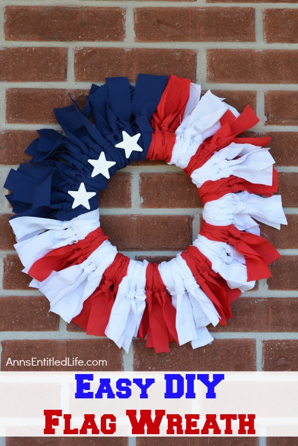 A red, white, and blue wreath with several stars hanging on a brick wall