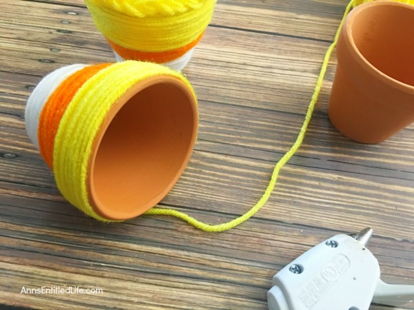 DIY Candy Corn Pots. These DIY Candy Corn Pots are simple to make. Dress up your pots for autumn or Halloween with this sweet candy corn decoration. Perfect for planting herbs in the fall for your kitchen window, or to hold candy corn candy, Halloween treats or nuts on a sideboard, mantel or end table, these do it yourself candy corn posts are a nice touch of whimsical fall décor.