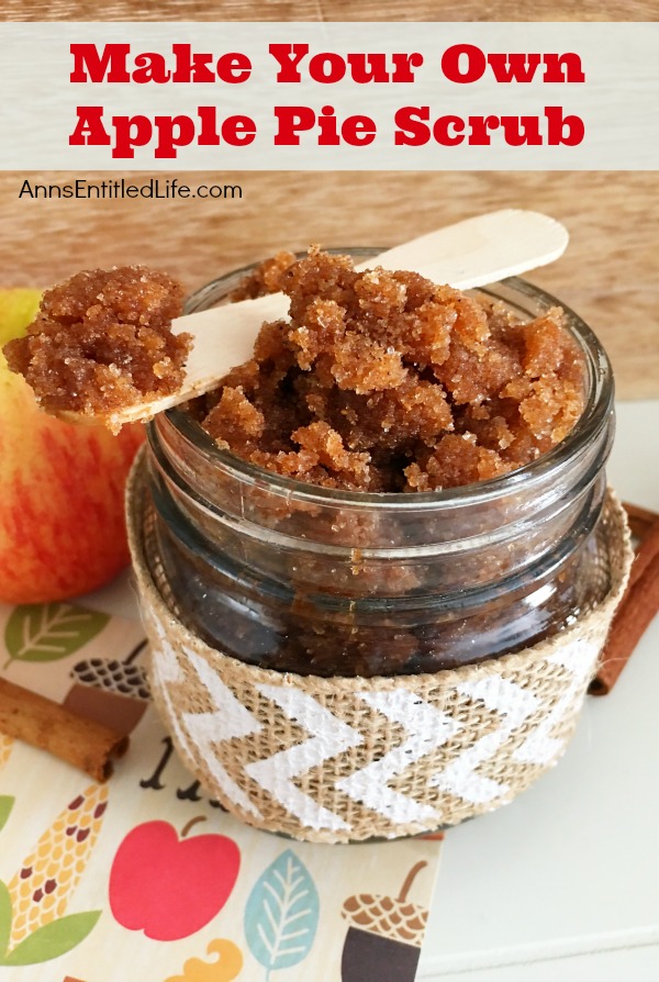 a small jar of apple pie sugar scrub on a autumn matt, a small wooden spoon has a quantity on it.