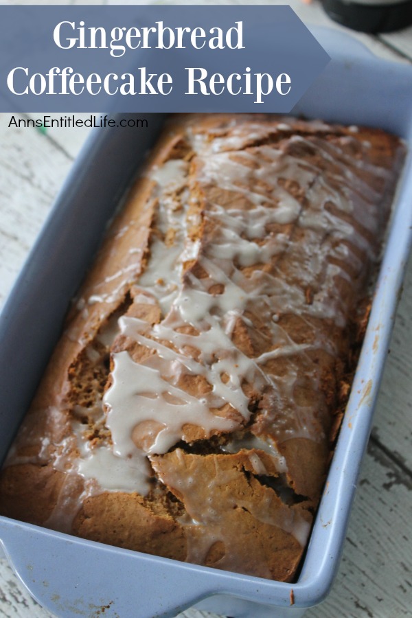 A loaf of iced gingerbread coffee cake in a blue loaf pan on a battered blue countertop.