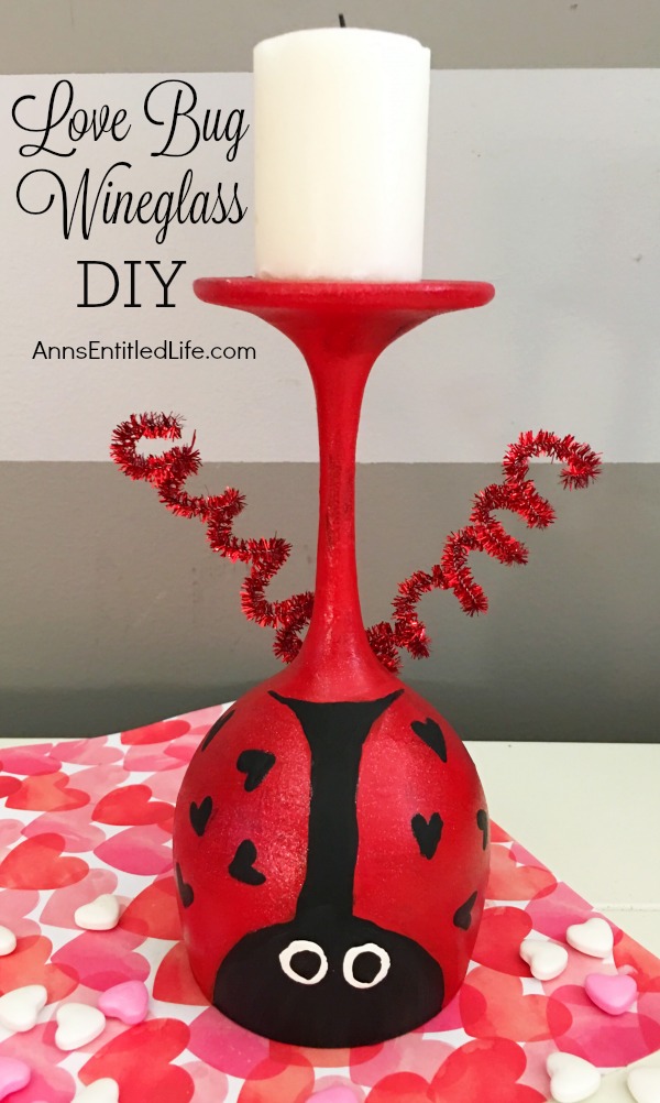 upside down wineglass painted like a love bug with antena and a candle, on top of a heart paper