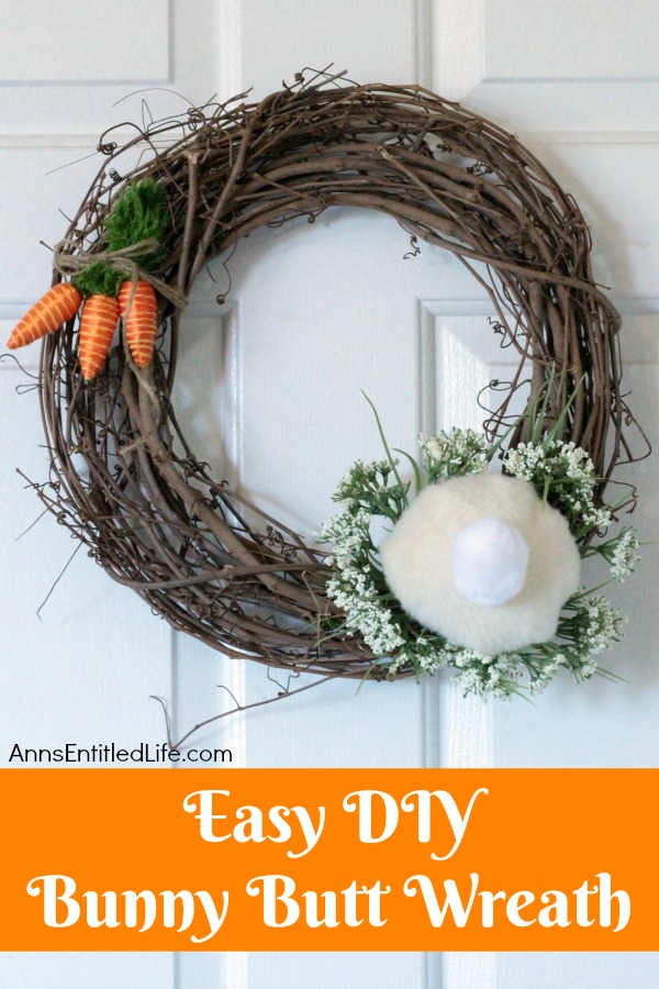 a gravevine wreath decorated to resemble a bunny butt hanging against a white door