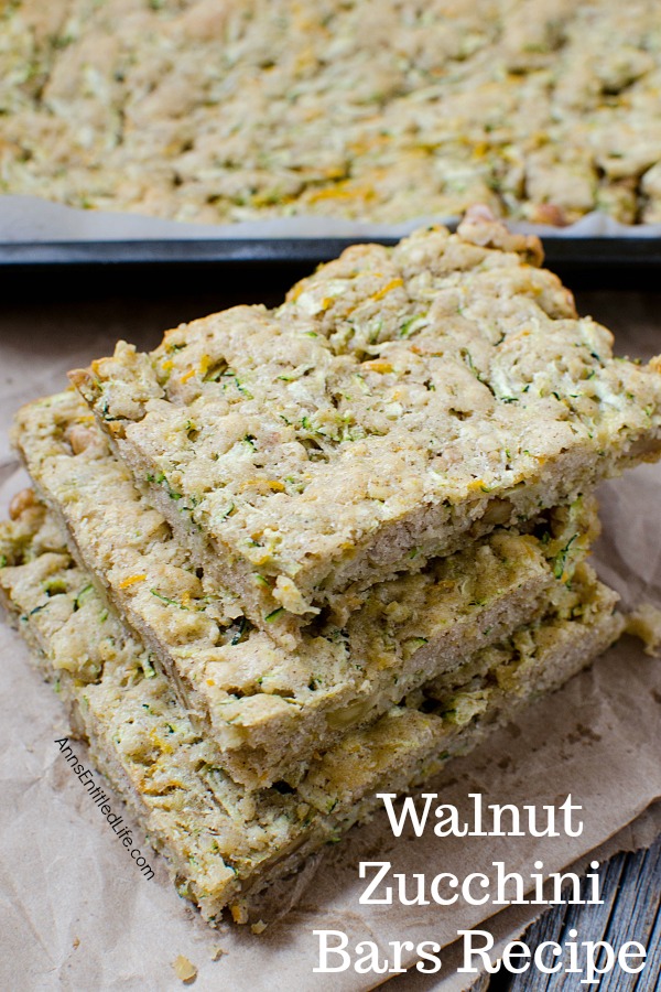 a stack of walnut zucchini bar squares on a napkin, the rest of the pan is in the background