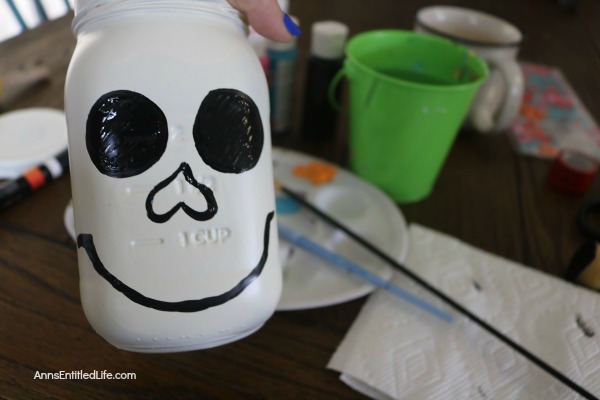 Sugar Skull Mason Jar Craft. This easy to make sugar skull is fashioned from an old Mason jar.  You can store kitchen utensils, candy (keep the lid!), etc in these jar for Halloween or to celebrate the Day of the Dead. Using old glass jars is a great way to get crafty at home and make your own cute décor at the same time.