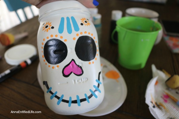 Sugar Skull Mason Jar Craft. This easy to make sugar skull is fashioned from an old Mason jar.  You can store kitchen utensils, candy (keep the lid!), etc in these jar for Halloween or to celebrate the Day of the Dead. Using old glass jars is a great way to get crafty at home and make your own cute décor at the same time.