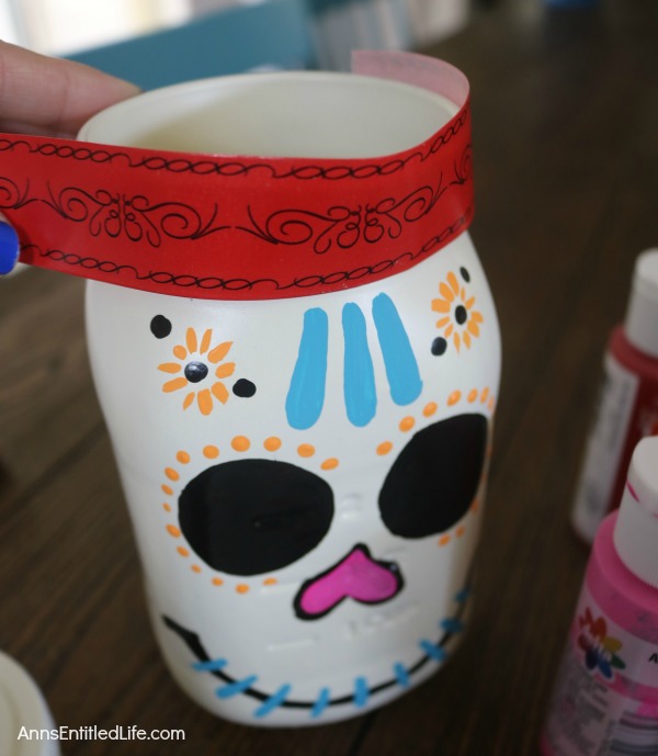 Sugar Skull Mason Jar Craft. This easy to make sugar skull is fashioned from an old Mason jar.  You can store kitchen utensils, candy (keep the lid!), etc in these jar for Halloween or to celebrate the Day of the Dead. Using old glass jars is a great way to get crafty at home and make your own cute décor at the same time.