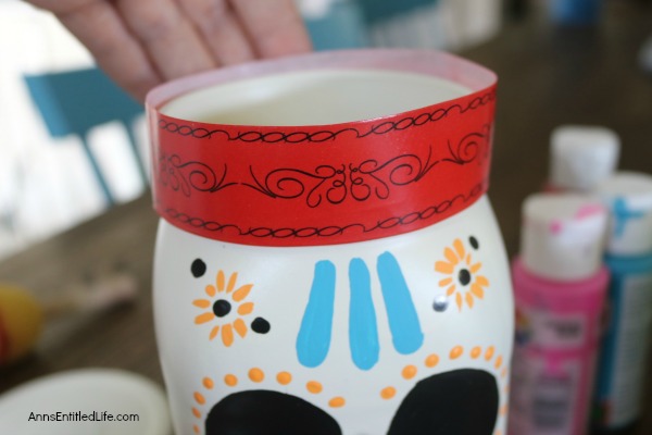 Sugar Skull Mason Jar Craft. This easy to make sugar skull is fashioned from an old Mason jar.  You can store kitchen utensils, candy (keep the lid!), etc in these jar for Halloween or to celebrate the Day of the Dead. Using old glass jars is a great way to get crafty at home and make your own cute décor at the same time.