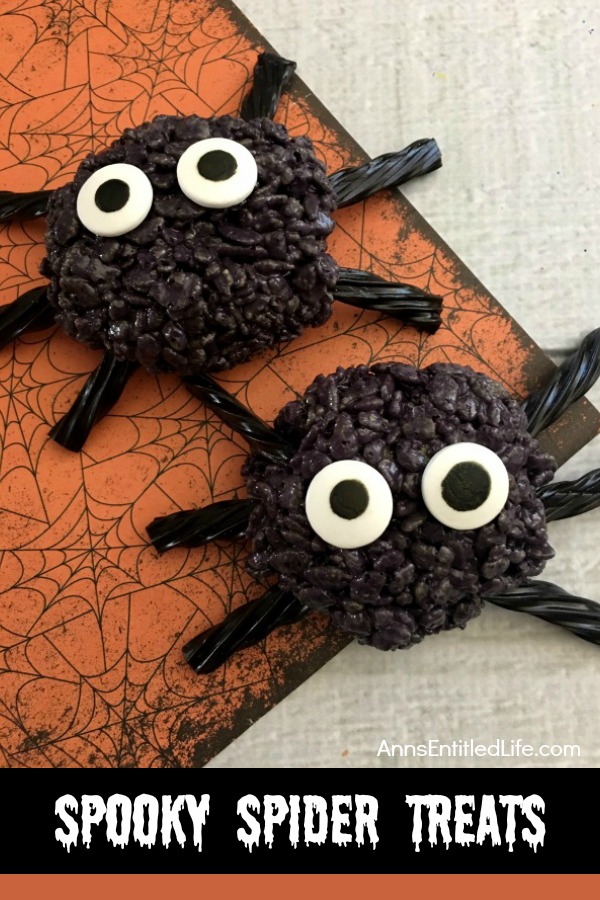 Two black crispy rice spiders set on an orange and black Halloween mat.