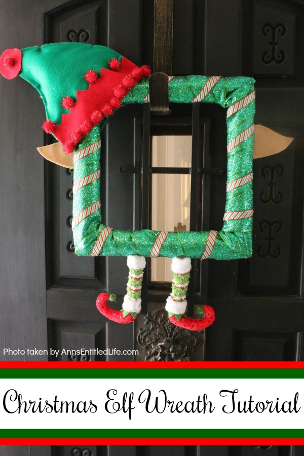 A square green elf wreath hanging against a dark brown door