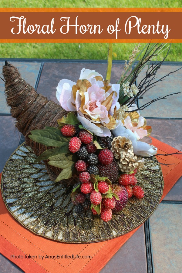 a twine horn of plenty stuffed with floral and beaded grapes sitting on a gold placemat which is sitting on an orange placemat