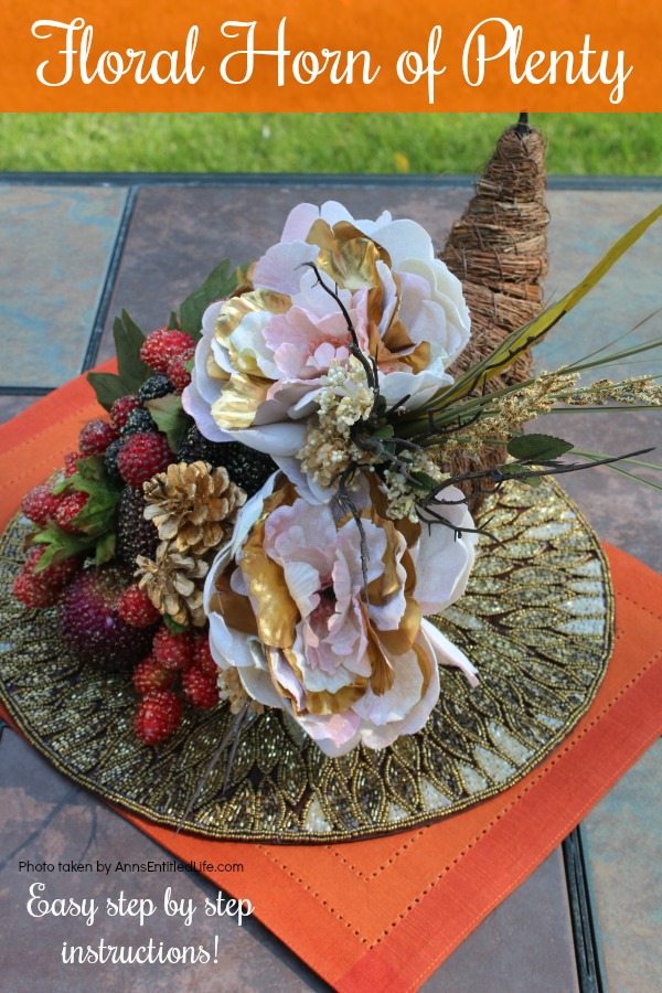 a twine horn of plenty stuffed with floral and beaded grapes sitting on a gold placemat which is sitting on an orange placemat