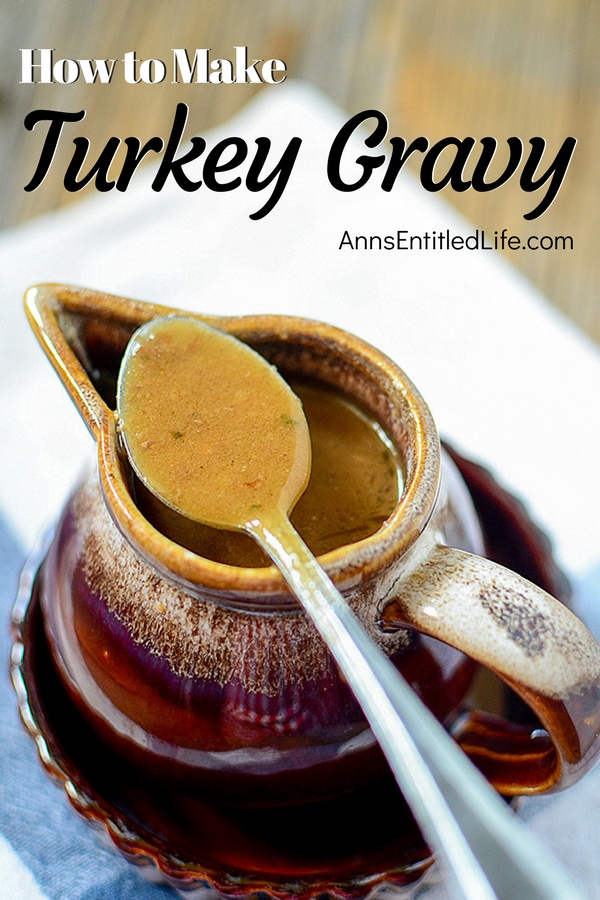 Turkey gravy in a brown ceramic pourer with a spoonful of turkey gravy resting across the top.