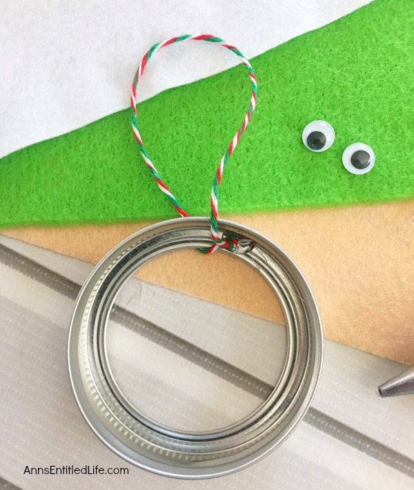 Elf Mason Jar Lid Ornament DIY. This easy to make Elf Mason jar lid ornament is simply adorable. This step by step tutorial has easy to follow directions so you can make one for your tree, to give as a gift, or to place on top of a present as a little something extra.