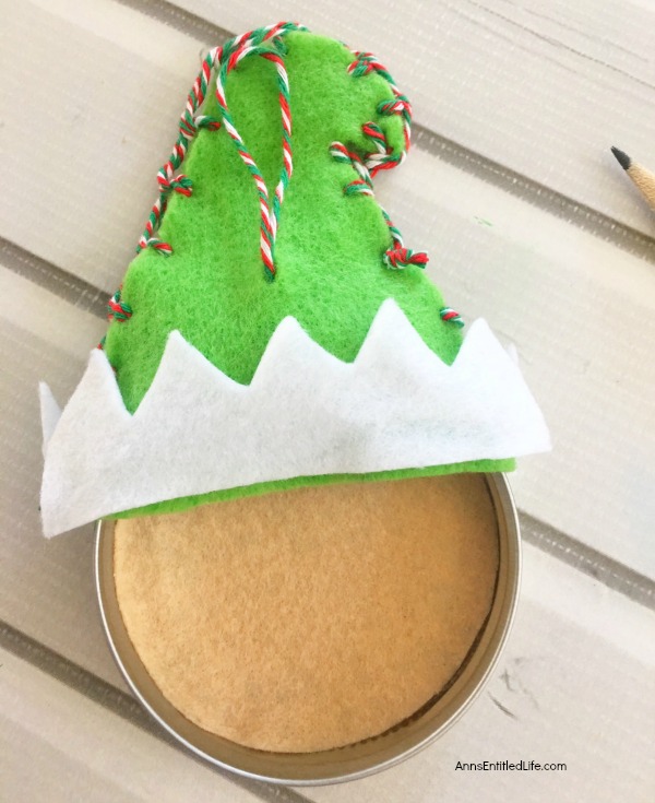 Elf Mason Jar Lid Ornament DIY. This easy to make Elf Mason jar lid ornament is simply adorable. This step by step tutorial has easy to follow directions so you can make one for your tree, to give as a gift, or to place on top of a present as a little something extra.