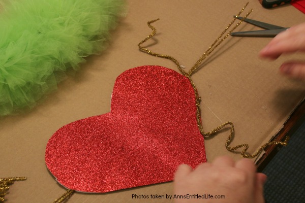 The Grinch Inspired Wreath DIY Tutorial. A beautiful Mr. Grinch inspired wreath sure to make even the coldest heart burst! This step by step tutorial is complete with (free) pdfs for the hat and heart for you to print and make exact. This wreath will look great on your front door, over your mantel, or on a wall. Truly unique holiday decor!