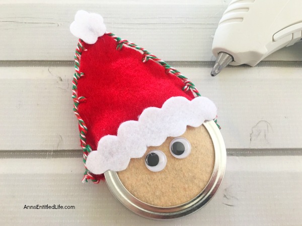 Santa Claus Mason Jar Lid Ornament DIY. Give your Christmas tree a personal touch and make your own ornaments this holiday season. Follow these step-by-step tutorial instructions to make this adorable Santa Claus Mason Jar Lid Ornament!