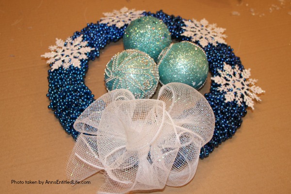 Snowflake Bead Wreath Craft DIY. This is a beautiful snowflake wreath that is perfect for door decor in the chilly winter months. You can fully customize this snowflake bead wreath for color, and ornaments. Simple to make, this lovely Snowflake Bead Wreath Craft is a real conversation piece.