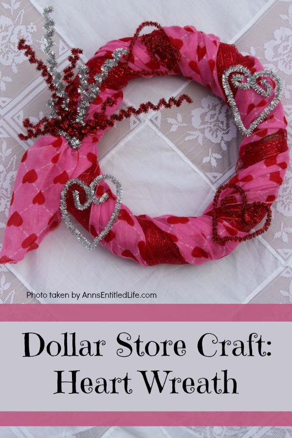 A round wreath decorated for Valentine's Day laying on a white tablecloth.