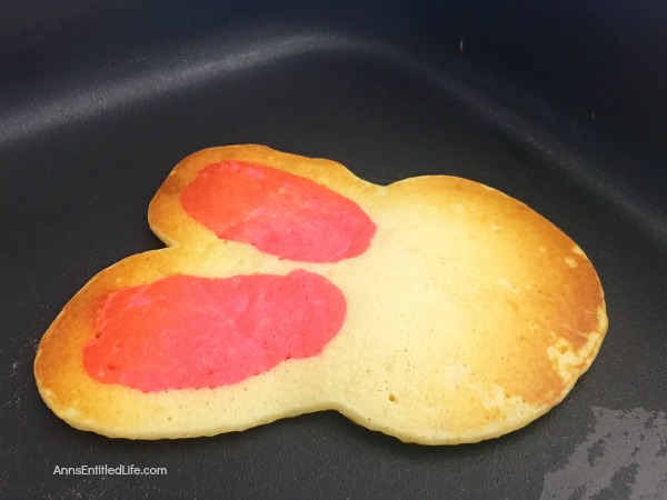 pancakes made in the shape of a rabbit head, decorated as bunnies on a white plate