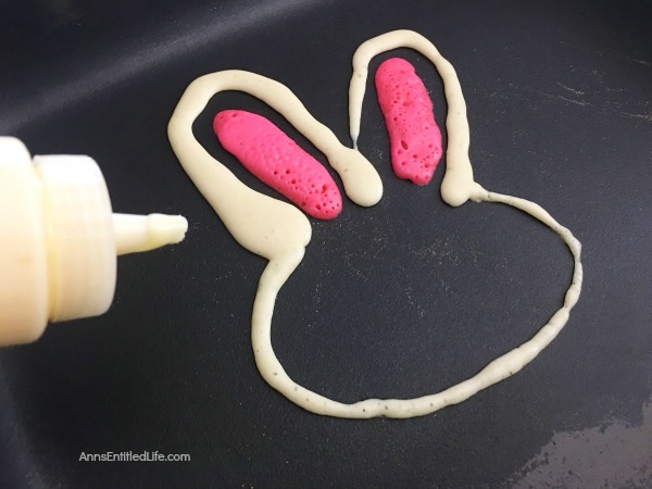 pancakes made in the shape of a rabbit head, decorated as bunnies on a white plate