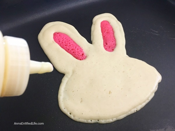 pancakes made in the shape of a rabbit head, decorated as bunnies on a white plate