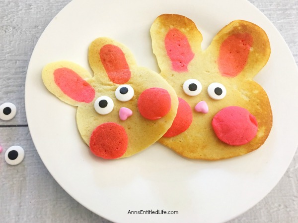 pancakes made in the shape of a rabbit head, decorated as bunnies on a white plate