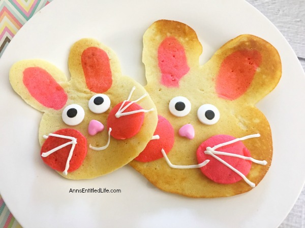 pancakes made in the shape of a rabbit head, decorated as bunnies on a white plate