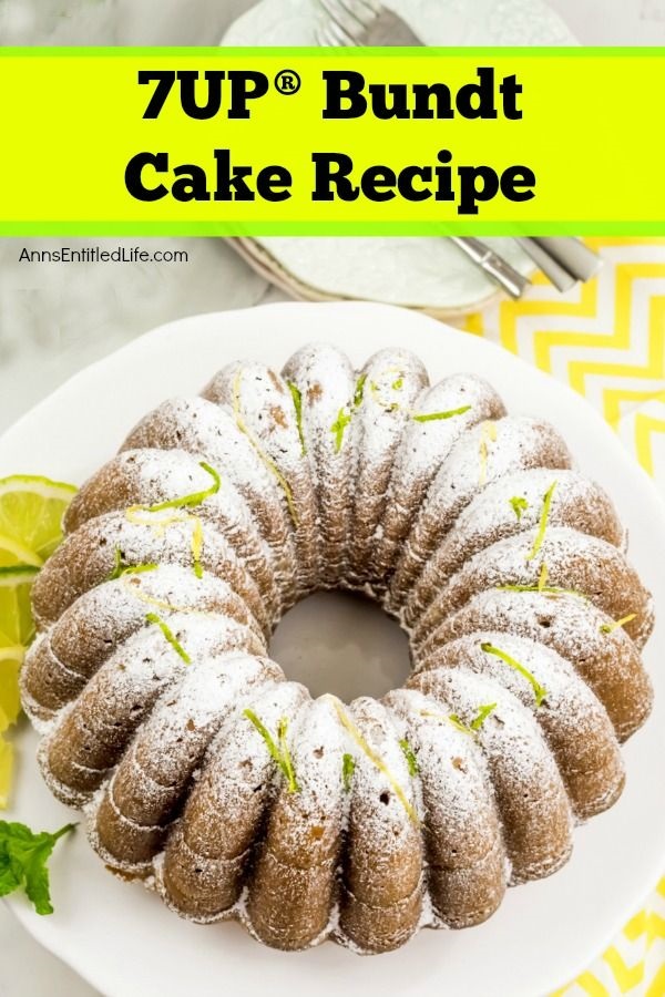 an overhead view of a whole 7UP Bundt cake on a white cake dish atop yellow and white chevron linen. There are white plates and cutlery above the bundt cake.