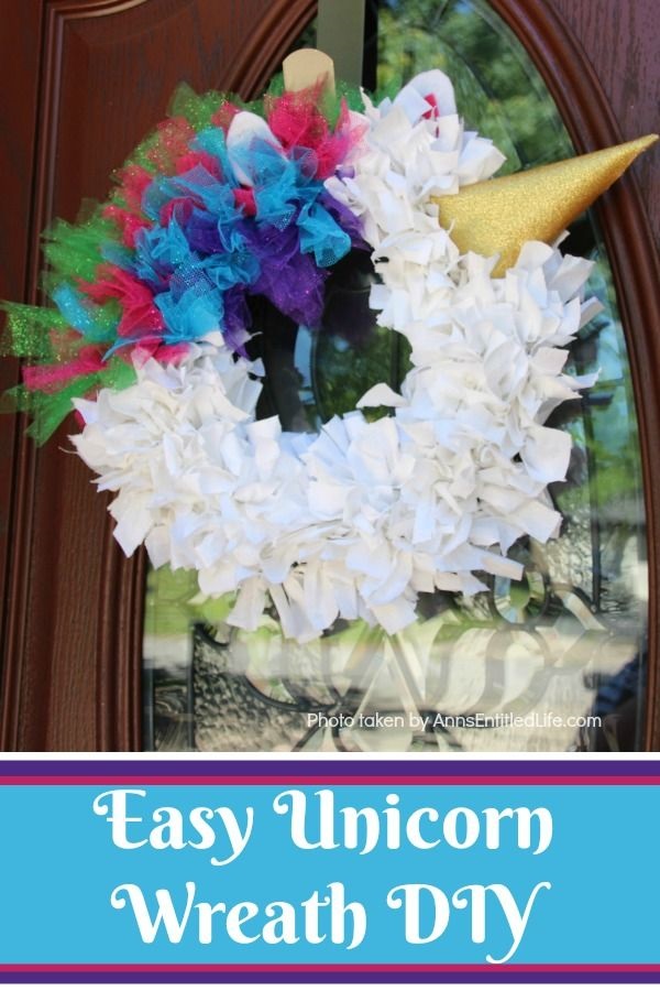 A unicorn wreath hanging against a brown door.