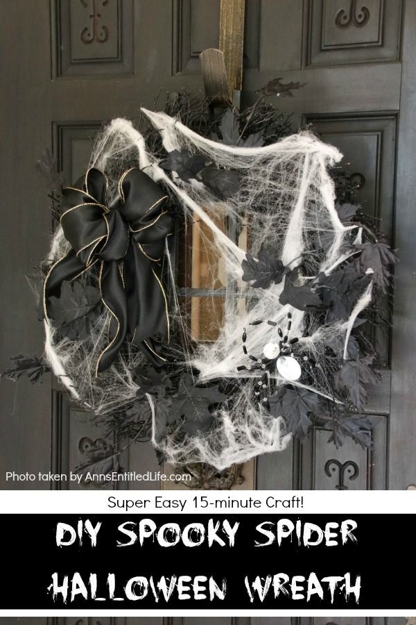 Black wreath, black leaves, and a giant diamond spider in the lower right of the wreath with a black bow diagonally across from  the sider is covered with faux spider web and hung on a dark brown door