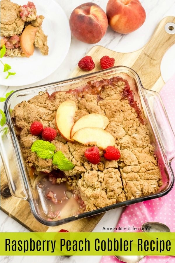 baked raspberry peach cobbler on a white dish with whipped cream and fresh raspberries