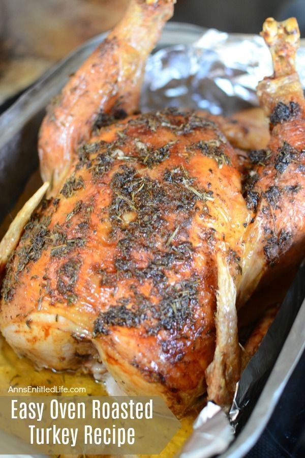 A whole, cooked turkey covered in herbs, sitting in a turkey pan.