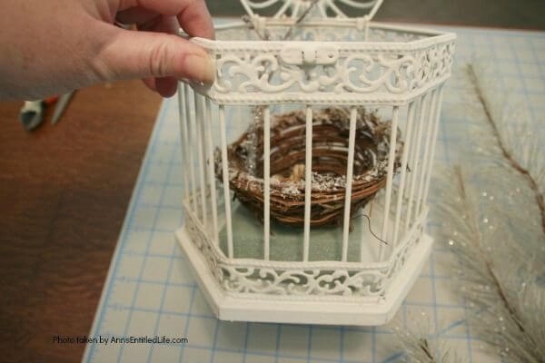 Have an old birdcage lying about that you would like to repurpose into a beautiful decor piece? This wonderful winter white birdcage decorating idea is a lovely DIY decorating piece for the holidays and beyond. This tells the story of a bird that has left the cage to fly south for the winter. His (or her) nest is empty, and he (or she) is off to parts unknown. This is not only a lovely winter piece, it could be used for wedding decor, a centerpiece, a front foyer piece (I always decorate my foyer!) or you could hang it as an empty birdcage in a Florida room or family room.