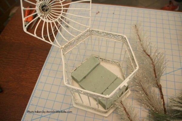 Have an old birdcage lying about that you would like to repurpose into a beautiful decor piece? This wonderful winter white birdcage decorating idea is a lovely DIY decorating piece for the holidays and beyond. This tells the story of a bird that has left the cage to fly south for the winter. His (or her) nest is empty, and he (or she) is off to parts unknown. This is not only a lovely winter piece, it could be used for wedding decor, a centerpiece, a front foyer piece (I always decorate my foyer!) or you could hang it as an empty birdcage in a Florida room or family room.