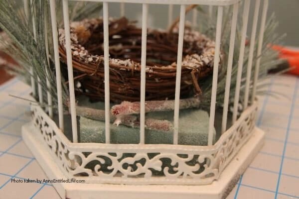 Have an old birdcage lying about that you would like to repurpose into a beautiful decor piece? This wonderful winter white birdcage decorating idea is a lovely DIY decorating piece for the holidays and beyond. This tells the story of a bird that has left the cage to fly south for the winter. His (or her) nest is empty, and he (or she) is off to parts unknown. This is not only a lovely winter piece, it could be used for wedding decor, a centerpiece, a front foyer piece (I always decorate my foyer!) or you could hang it as an empty birdcage in a Florida room or family room.