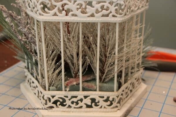 Have an old birdcage lying about that you would like to repurpose into a beautiful decor piece? This wonderful winter white birdcage decorating idea is a lovely DIY decorating piece for the holidays and beyond. This tells the story of a bird that has left the cage to fly south for the winter. His (or her) nest is empty, and he (or she) is off to parts unknown. This is not only a lovely winter piece, it could be used for wedding decor, a centerpiece, a front foyer piece (I always decorate my foyer!) or you could hang it as an empty birdcage in a Florida room or family room.