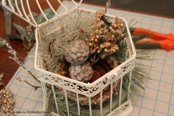 Have an old birdcage lying about that you would like to repurpose into a beautiful decor piece? This wonderful winter white birdcage decorating idea is a lovely DIY decorating piece for the holidays and beyond. This tells the story of a bird that has left the cage to fly south for the winter. His (or her) nest is empty, and he (or she) is off to parts unknown. This is not only a lovely winter piece, it could be used for wedding decor, a centerpiece, a front foyer piece (I always decorate my foyer!) or you could hang it as an empty birdcage in a Florida room or family room.