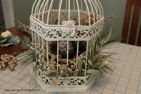 Have an old birdcage lying about that you would like to repurpose into a beautiful decor piece? This wonderful winter white birdcage decorating idea is a lovely DIY decorating piece for the holidays and beyond. This tells the story of a bird that has left the cage to fly south for the winter. His (or her) nest is empty, and he (or she) is off to parts unknown. This is not only a lovely winter piece, it could be used for wedding decor, a centerpiece, a front foyer piece (I always decorate my foyer!) or you could hang it as an empty birdcage in a Florida room or family room.