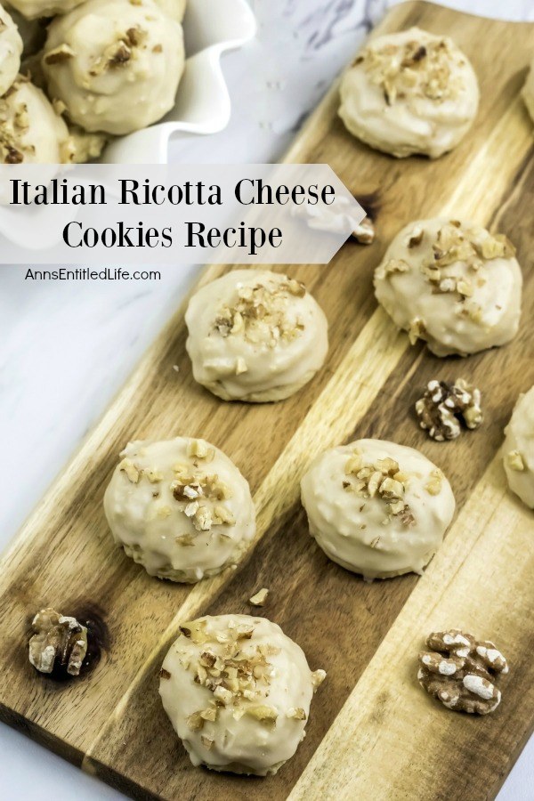 Italian Ricotta cheese cookies on a cutting board. There are walnuts placed in between the cookies. To the upper left is a white plate of more cookies