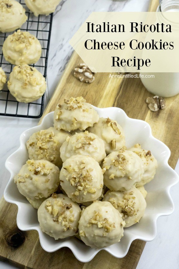 Italian Ricotta cheese cookies in a white, fluted plate. There are more cookies on a wire rack in the upper left.