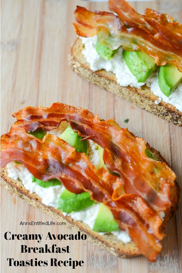 Two pieces of bread with avocado, bacon, and other toastie ingredients, on top of a wooden tray