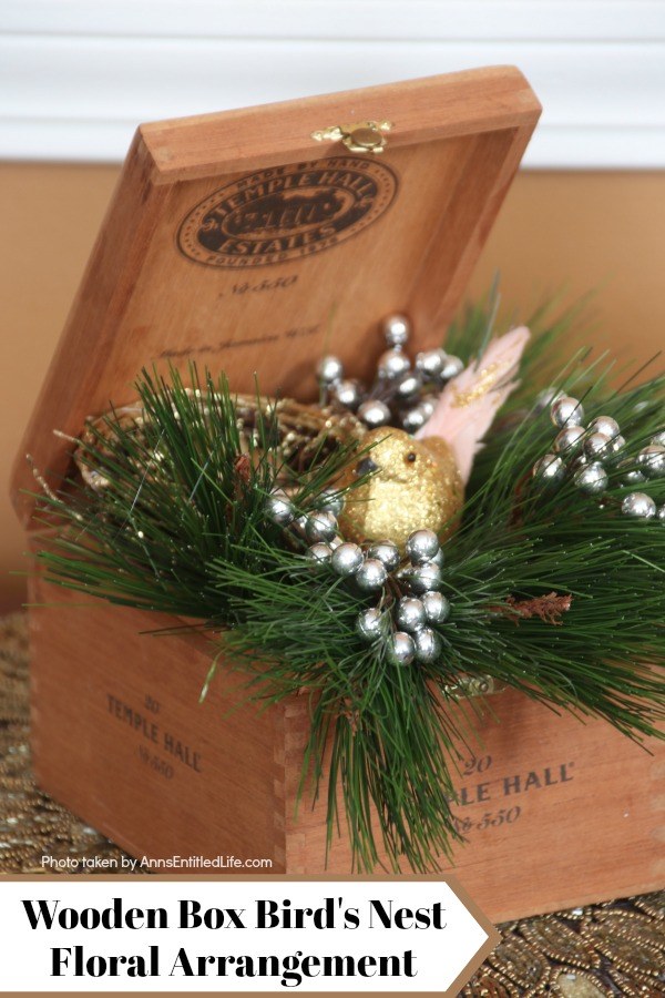 A floral arrangement in a wooden box featuring an artificial bird