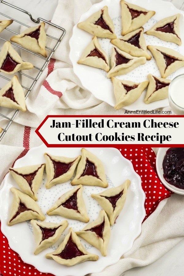 An overhead view of two white plates willed with jam cookies (triangular shaped cookies with jam in the middle). A rack has more jam cookies in the upper left.