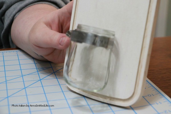 Farmhouse Décor: Jar Flower Holder. This adorable little jar flower holder is easy to make, rustic decor. Great indoors or outdoors decorating, this sweet little bud vase fills in that small section of open wall space perfectly. The step-by-step tutorial will show you how to make this simple DIY farmhouse décor jar flower holder inexpensively.