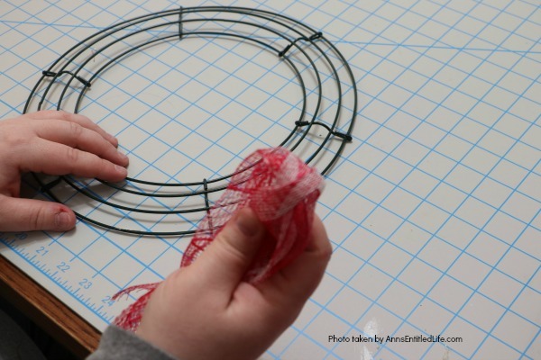 Patriotic Farmhouse Wreath DIY. This simple to make, rustic style American patriotic mesh farmhouse wreath is wonderful for outdoor or indoor display. Using only three materials and scissors, this easy to make wreath comes together in about 15 minutes. If you are looking for a patriotic holiday wreath, this little beauty is it!