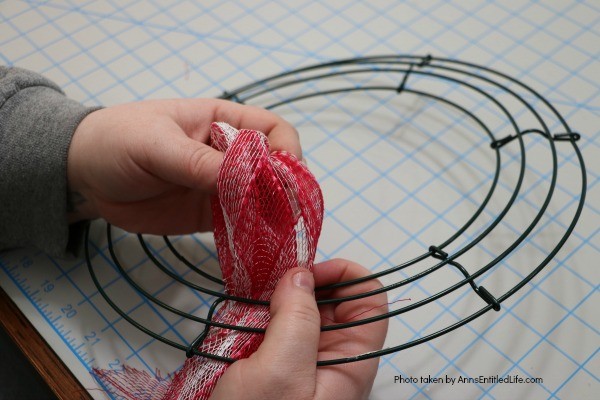 Patriotic Farmhouse Wreath DIY. This simple to make, rustic style American patriotic mesh farmhouse wreath is wonderful for outdoor or indoor display. Using only three materials and scissors, this easy to make wreath comes together in about 15 minutes. If you are looking for a patriotic holiday wreath, this little beauty is it!