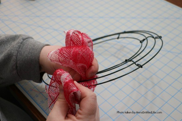 Patriotic Farmhouse Wreath DIY. This simple to make, rustic style American patriotic mesh farmhouse wreath is wonderful for outdoor or indoor display. Using only three materials and scissors, this easy to make wreath comes together in about 15 minutes. If you are looking for a patriotic holiday wreath, this little beauty is it!